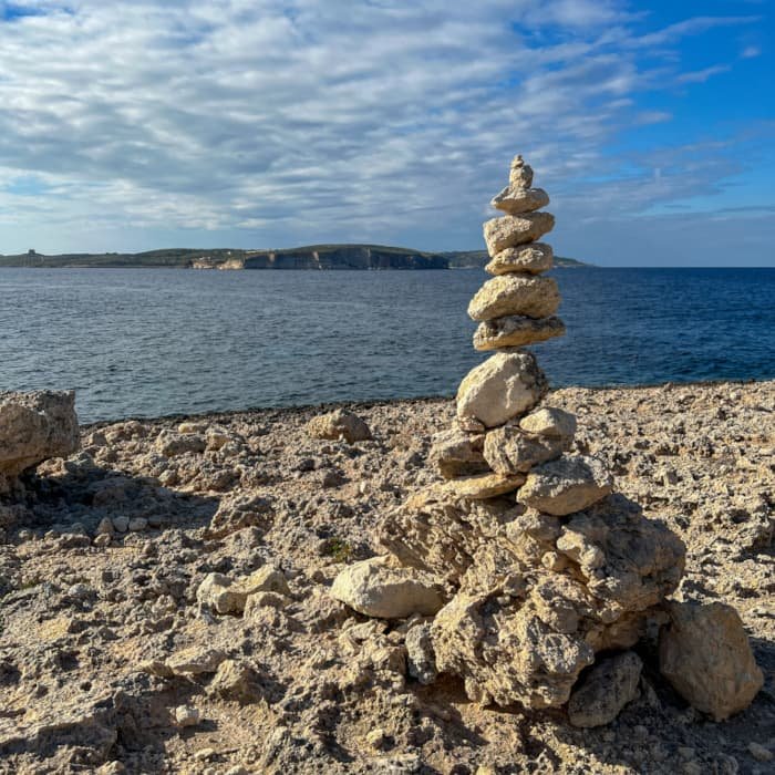 Perfect gebalanceerde, gestapelde stenen aan de kust van Malta, die de structuur en flow van een goed ontworpen digitaal ecosysteem symboliseren.